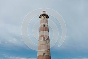 Low-angle of Farol de Aveiro lighthouse tower with red stripes against blue sky photo
