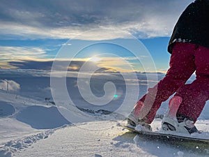 LOW ANGLE: Female snowboarder rides down ungroomed slopes near a ski resort. photo