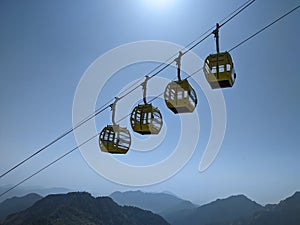 Low-angle of four yellow cable cars on the rope against a blue sky