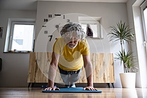 Low angle front view of a senior man living an active life working out at home