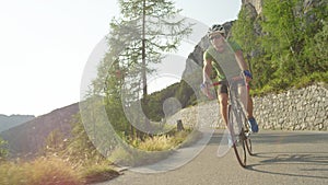 LOW ANGLE: Golden sunbeams shine on man road cycling in the sunny mountains.