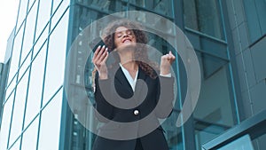Low angle happy excited Caucasian business woman celebrate victory near skyscraper building joyful girl businesswoman