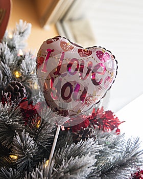 Low angle of a heart-shaped "I love you" balloon on a Christmas tree - concept of holidays