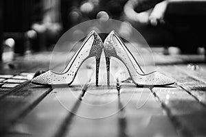 Low angle of high heels glitter women shoes place on the wooden floor in black and white