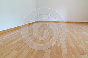 Low angle horizontal view of new wooden parquet flooring in a bright light and white apartment room