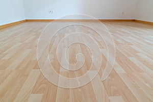 Low angle horizontal view of new wooden parquet flooring in a bright light and white apartment room