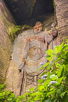 Low angle on the hyaku-shaku kannon buddha of Mount Nokogiri with a purple hydrangeas flower.