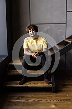 Low angle indian man sitting on steps at home