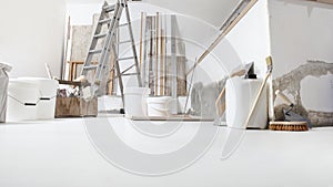Low angle of indoor shot of construction or building site of home renovation with tools on white floor with paint buckets and