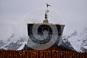 Low angle of the Kedarnath Temple decorated with marigold flower curtains in foggy weather photo