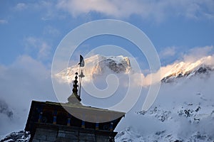 Low angle of the Kedarnath temple with the Garhwal Himalayas snow peaks in clouds in the background photo