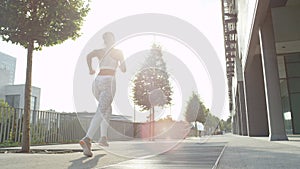 LOW ANGLE, LENS FLARE: Active woman exercising alone in pleasant morning sun.