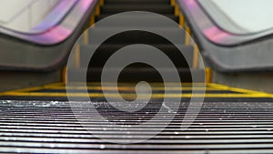 Low angle looped perspective view of modern escalator stairs. Automated elevator mechanism. Yellow line on stairway illuminated