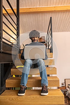 Low angle man sitting on steps working on laptop