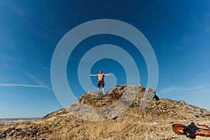 Low angle of a man standing on top of the castle of Melhor, Portugal against a blue sky photo