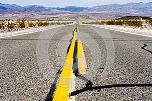 Low angle middle of the road view through Death Valley National Park California State Route 190, with a view of the Sierra