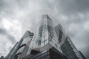 A low angle photo of a modern glassy building, cloudy day