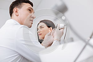 Low angle picture of professional doctor checking female ear