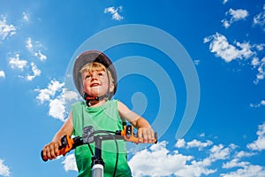 Low angle portrait of a little smiling boy ride small bicycle