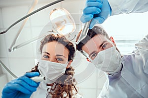 Low angle portrait of male and female dentists wearing masks at dental clinic photo