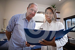 Low angle portrait of smiling senior male patient and female doctor with file