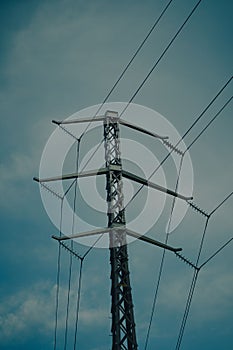 Low angle of a pylon tower supporting electrical cables against the evening sky