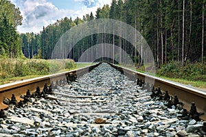 Low angle railway view with forest and cloudy sky in Russia