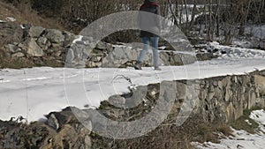 Low angle reverse tracking shot of a girl walking on a snowy path