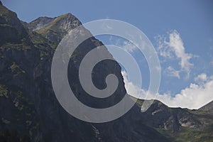 Low-angle of a ridged, lerk mountain with sunlit and clear sky background