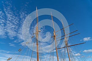 Low-angle of a sailing boat mast with a blue cloudy sky in the background