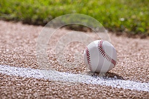 Low angle selective focus view of a baseball on a basepath in sunlight