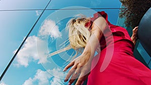 Low angle of sensual female dancer against blue glass wall of skyscraper