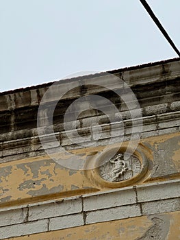 Low angle shot of an ancient Roman symbol on the brick wall of an old building under a clear sky