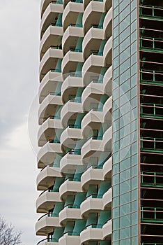 Low angle shot of balconies of a high-rise building with blue glasses under the light