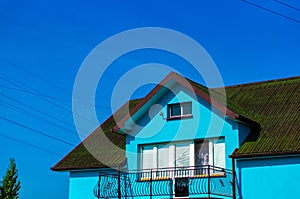 Low angle shot of a blue house with a green rooftop under a clear blue sky