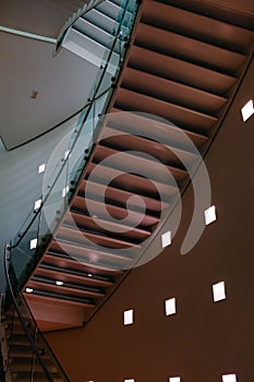 Low angle shot of a brown handrail in a building with square lamps in the walls