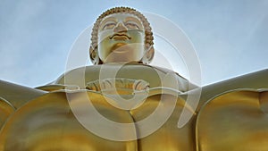 Low angle shot of a buddha gold statue with blue sky in the background