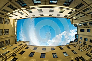 Low angle shot of building with windows and cloudy sky background. Courtyard city fisheye up view