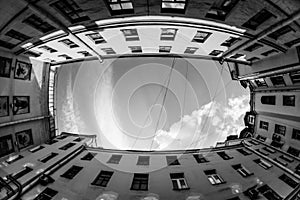 Low angle shot of building with windows and cloudy sky background. Courtyard city fisheye up view. black and white