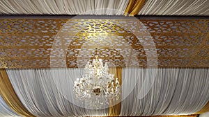 Low angle shot of a chandelier in the ceiling with white and yellow textiles