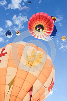 Low angle shot of colorful hot air balloons rising high in the blue sky