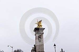 Low angle shot of the column with golden statue on the Alexander III Bridge in Paris