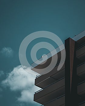 Low angle shot of corner balconies of modern apartment building on blue cloudy sky background