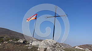 Low angle shot of a cross and the Armenian flag on a hill