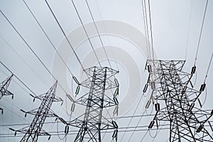 Low angle shot of electricity towers and wires under a clou