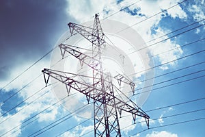 Low angle shot of electricity wires under the beautiful cloudy sky on a bright and sunny day