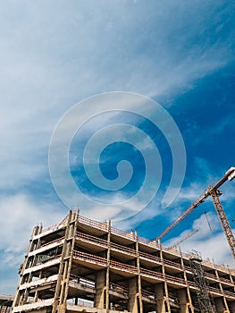 Low angle shot of elevating crane and building construction site