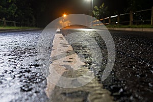 A low angle shot of an empty road on a misty night with street lights and a shallow depth of field