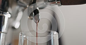 Low angle shot of espresso pour from coffee machine ingo glass cup photo