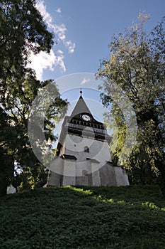 Low-angle shot of a Gothic Protestant Church of Avas, tucked among green trees on a sunny day photo